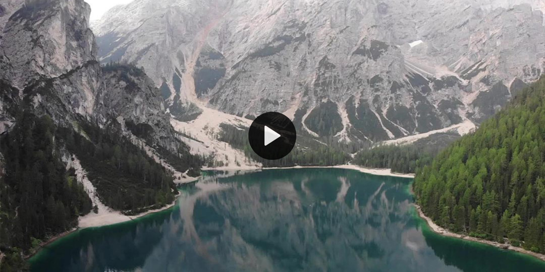 A mountain and a lake with a play button overlaid on top.